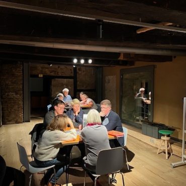 Eine Gruppe von Menschen sitzt an einem Tisch. Sie denken eifrig nach.